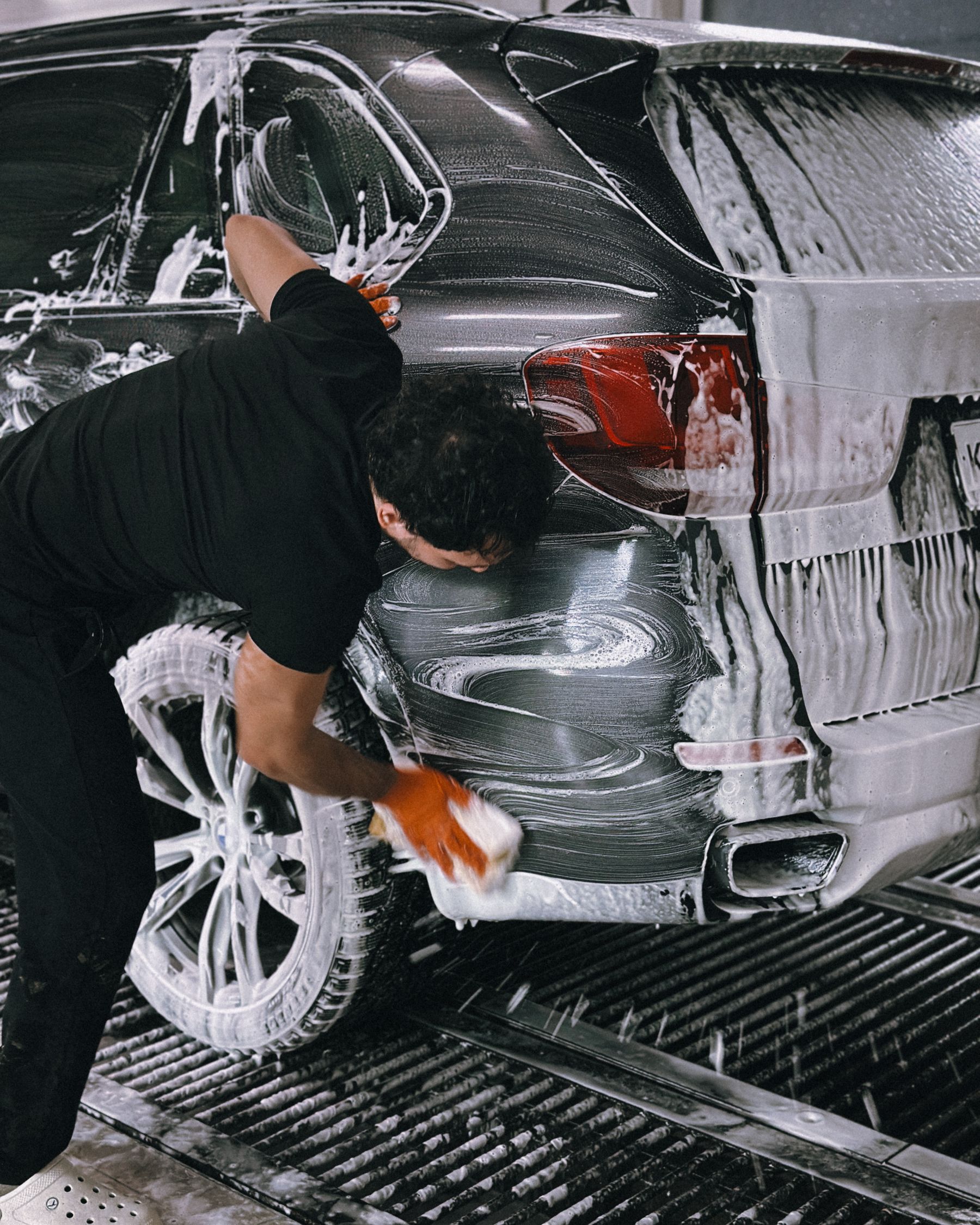 A dark vehicle receiving a careful exterior wash